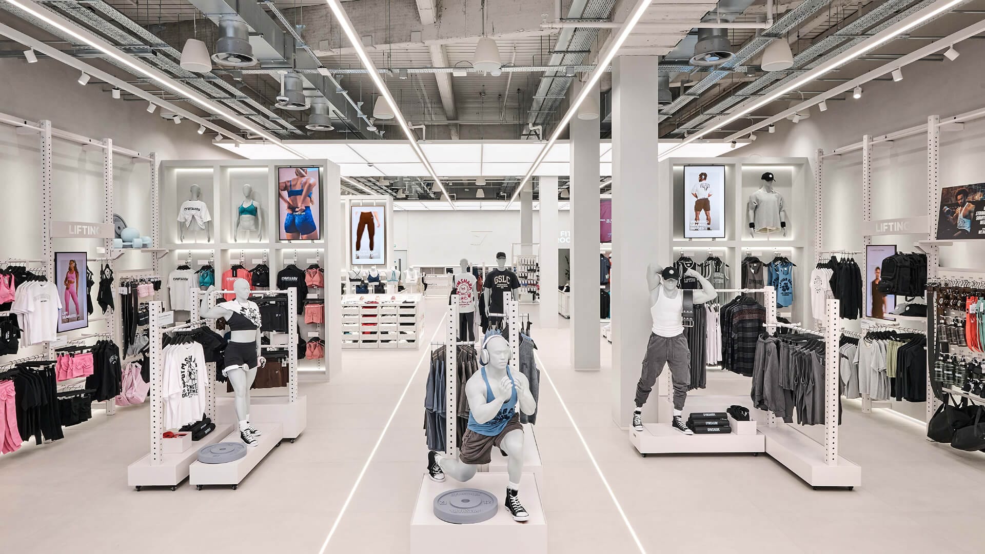 Gymshark Stratford store full interior view with dynamic exercise pose mannequins in central aisle, retail interior design by On Poynt Creative